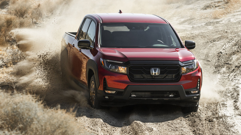 red 2023 Honda Ridgeline Sport driving on dirt road