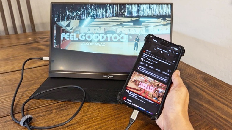 An iPhone playing a YouTube video is connected to the Arzopa portable monitor