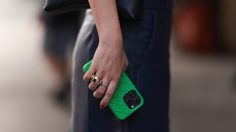 A woman holding an iPhone with a green case