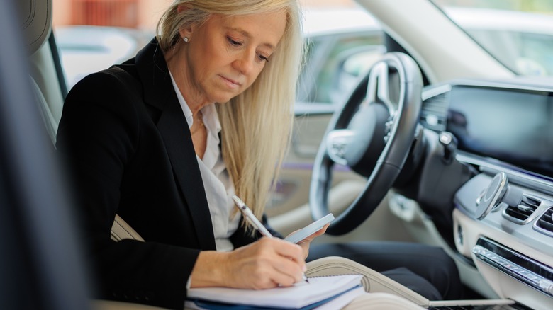 Woman taking notes in driver's seat