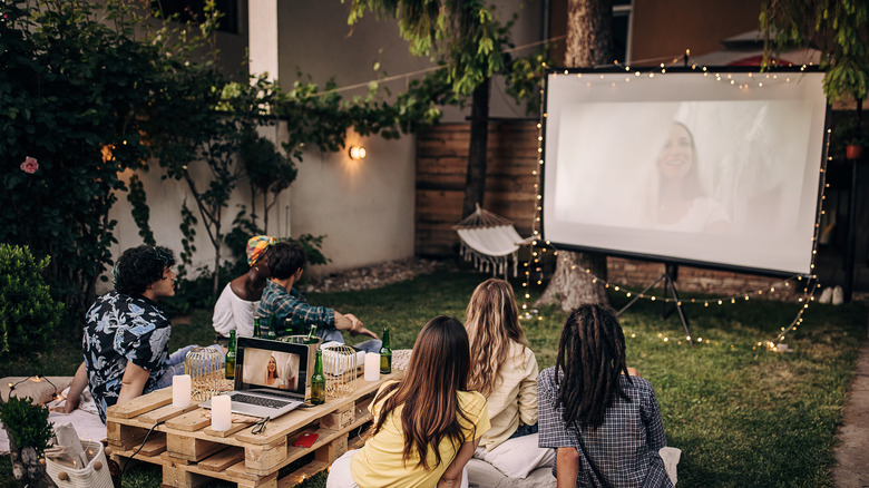 people watching the screen outdoors