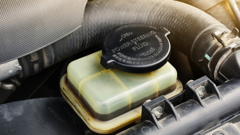 an automotive power steering fluid reservoir with what appears to be relatively dirty fluid