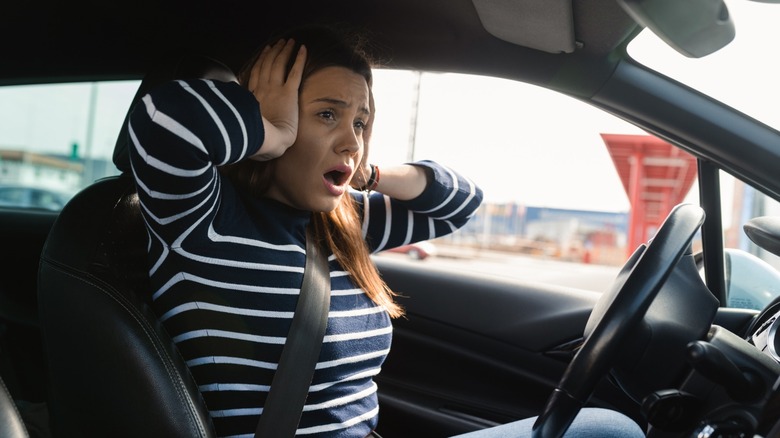 A driver covering their ears due to worrisome noises