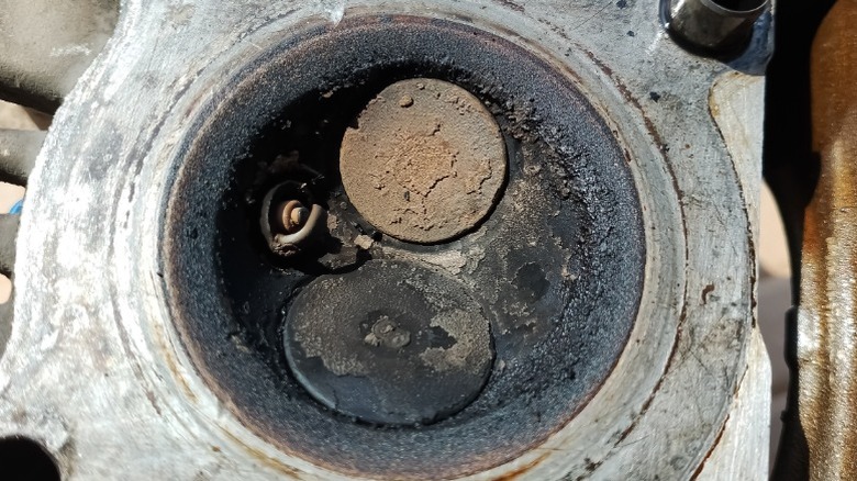 a closeup image of an engine cylinder head with severe carbon buildup