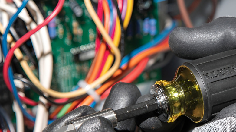 Person holding Klein stubby screwdriver in front of wires