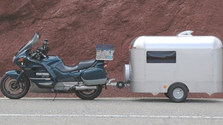 Motorcycle with camping trailer in front of red cliff