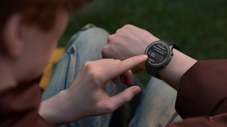 A user interacts with the OnePlus Watch 2R outdoors