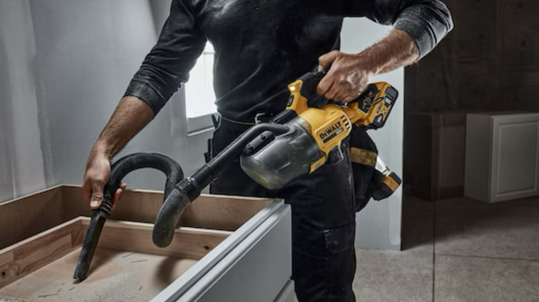 Person using a DeWalt vaccum to pick up debris