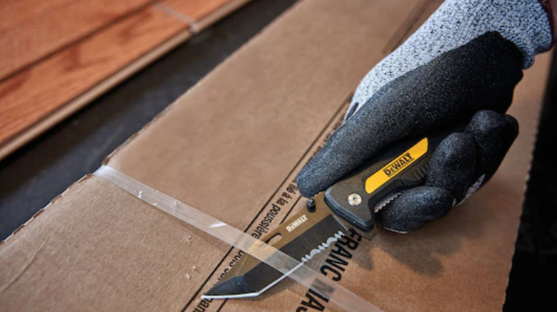 Person using a DeWalt knife to cut open a box