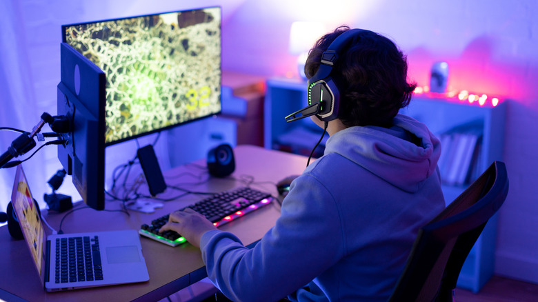 A gamer sits at a desk, wearing a headset.