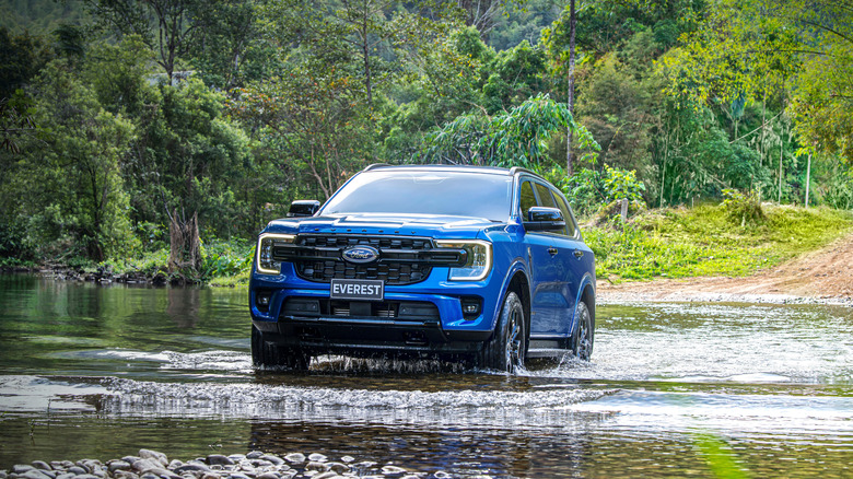 A blue Ford Everest Sport fording a river, front 3/4 view