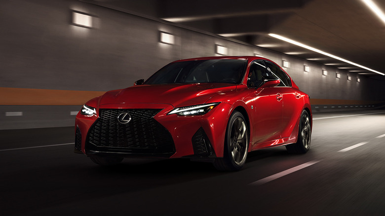 The 2025 Lexus IS500 F Sport Performance in red on the move in a tunnel, front 3/4 view