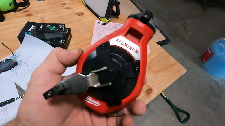 Man holding Milwaukee bold line chalk reel over work table