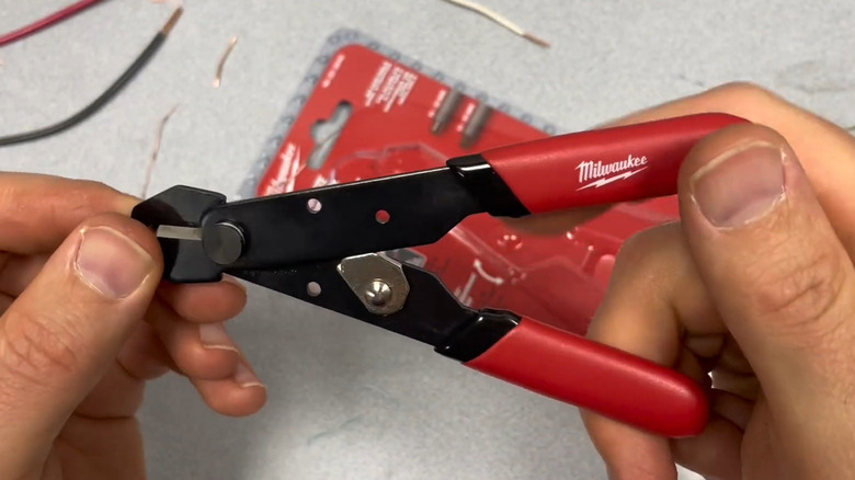 Two hands holding wire strippers over table