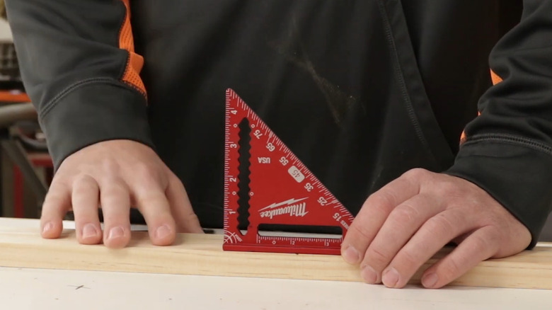 Man placing Milwaukee trim square on plank of wood