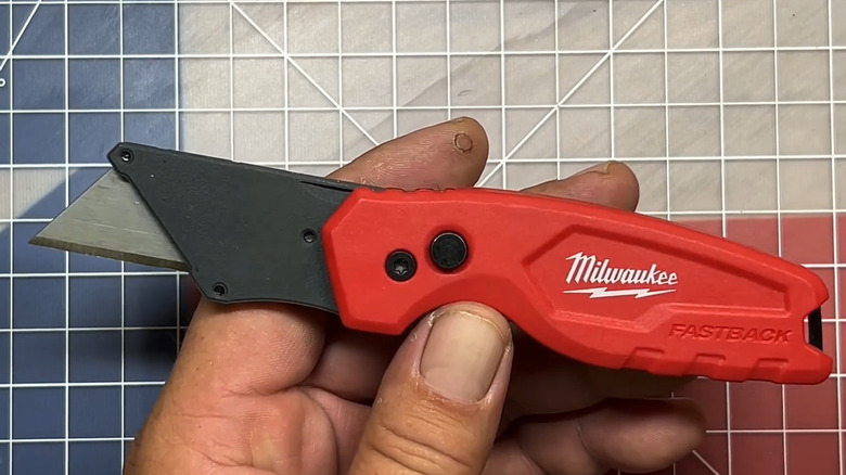 Man holding Milwaukee utility knife over cutting board