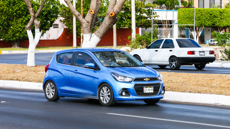 A blue Chevy Spark driving on a city street