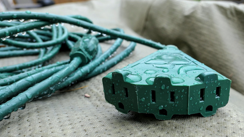 Green extension cord covered in water droplets.