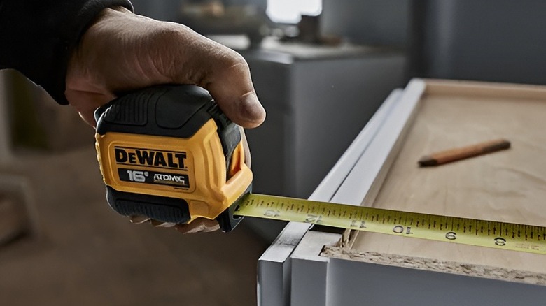 Man stretching out DeWalt tape measure to the edge of the table