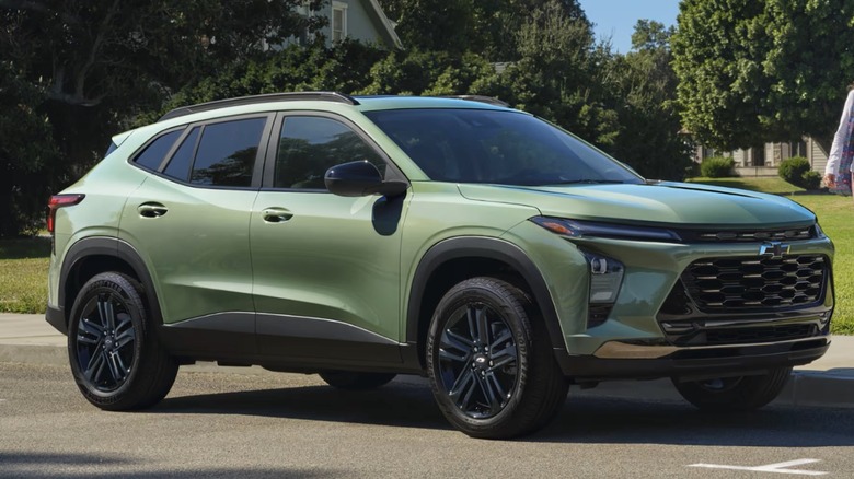 Cacti Green 2025 Chevy Trax parked on the roadside with trees and buildings in the background