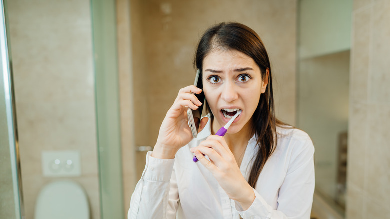 Woman brushing teeth while on phone