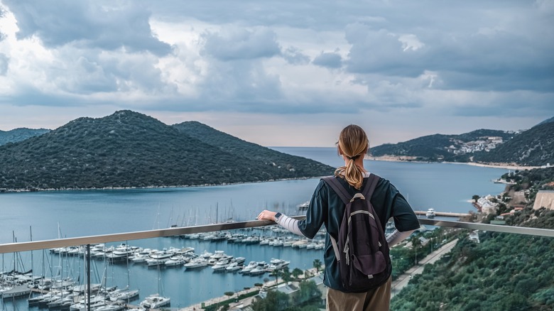 Woman looking at port with hills and clouds in the background