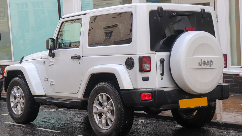 Rear view of a white 2018 Jeep Wrangler JK Edition parked by the sidewalk