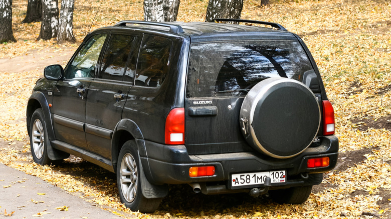 An older-generation black Suzuki Grand Vitara parked on the side of the road.