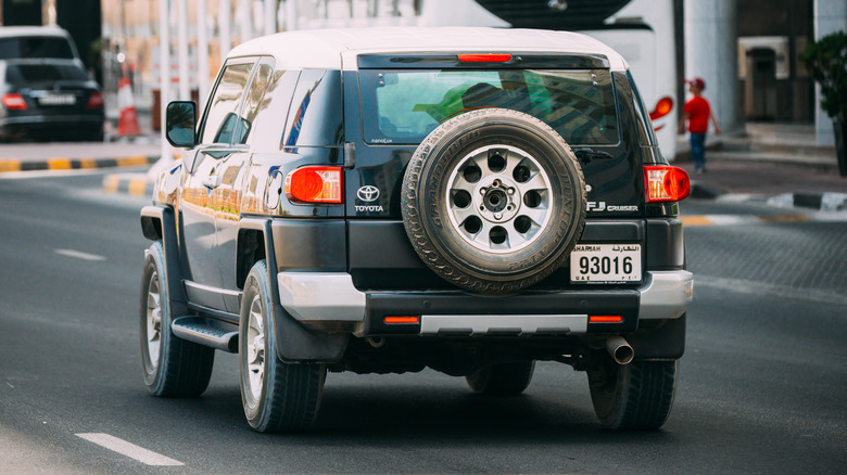 A Toyota FJ Cruiser with an exposed rear-mounted spare tire running on the road.