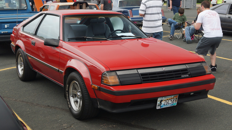 A red A60 Toyota Celica on a parking lot, front 3/4 view