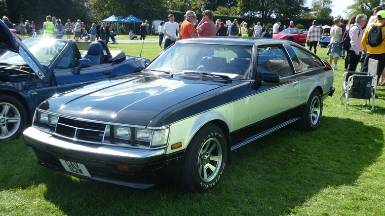 A first generation Toyota Celica Supra at an open air car show, front 3/4 view