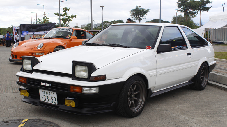 A white Toyota Sprinter Trueno with a black bumper at a car show, front 3/4 view