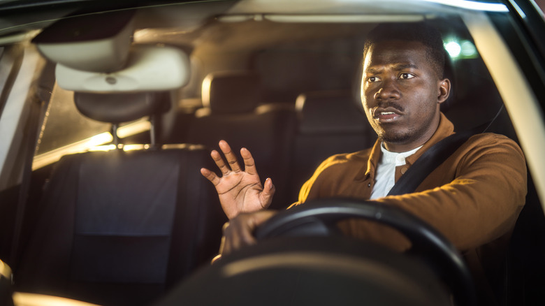 A driver looks worried as he tries to to avoid a car accident.