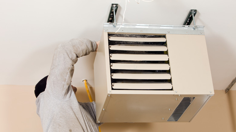 Person working on a ceiling mounted garage heater