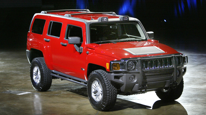 A red Hummer H3 at a car show, front 3/4 view