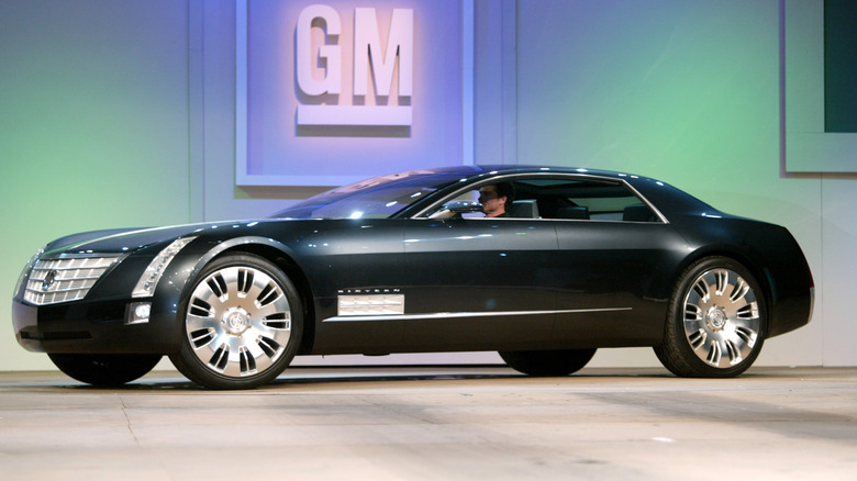 A Cadillac Sixteen concept in front of a GM sign, front 3/4 view