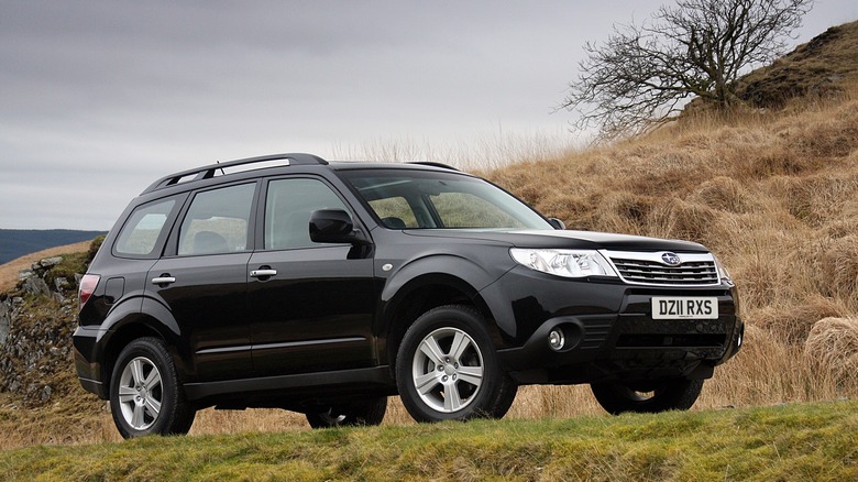 A third generation Subaru Forester in black on a hilly scene, front 3/4 view