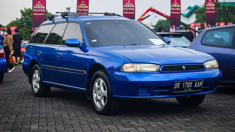 A blue second generation Subaru Legacy wagon at a car show, front 3/4 view