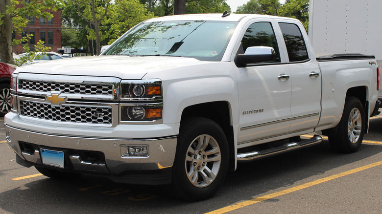 White Chevy SIlverado pickup with trailer parked in lot