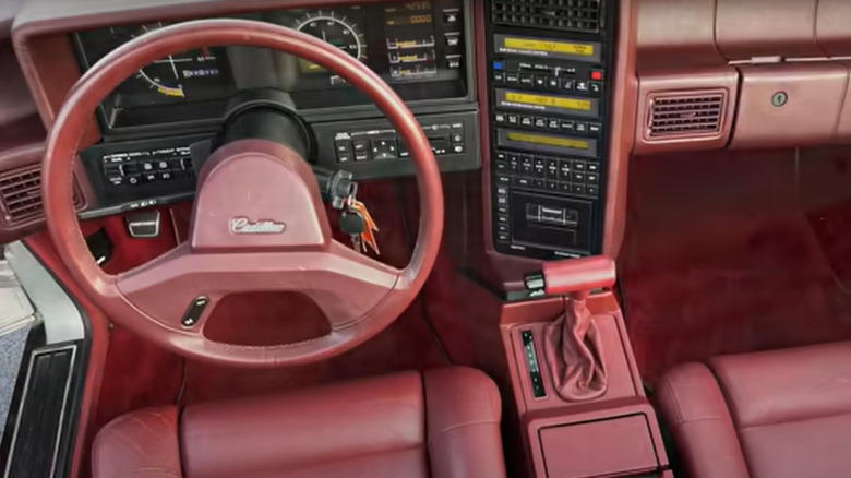 The dashboard of a Cadillac Allante in red trim, showing the steering wheel, instrument panel and many buttons