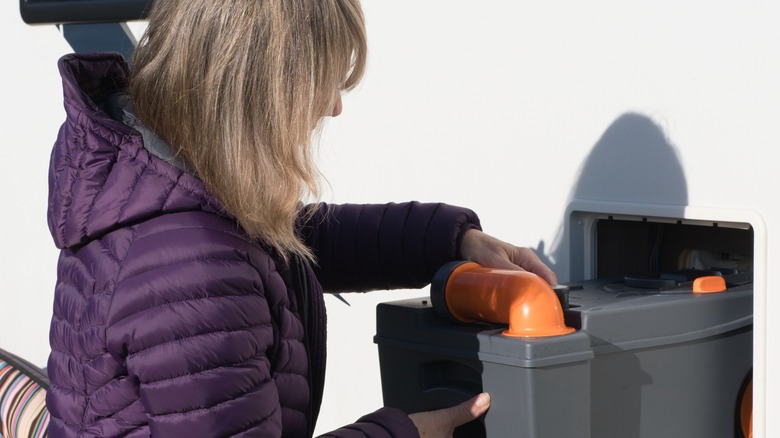 Woman withdrawing toilet cassette from RV