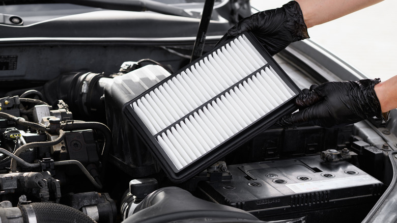 Mechanic installing new air filter in car engine