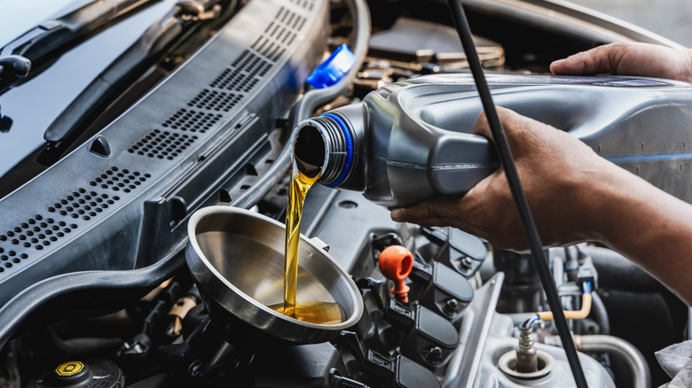 Mechanic pouring engine oil into vehicle