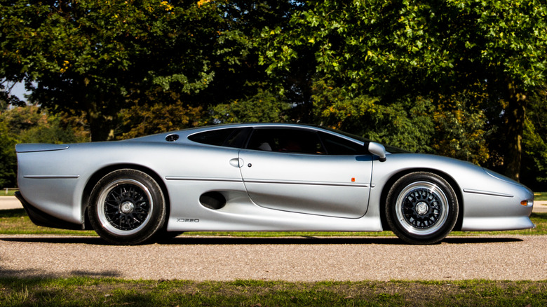 A silver Jaguar XJ220 on a country road.