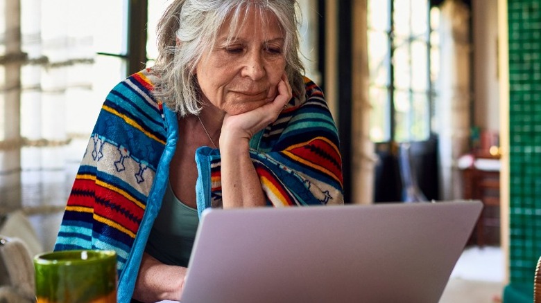 Old woman using a laptop on a table