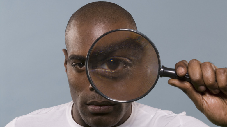 Man looking through magnifying glass