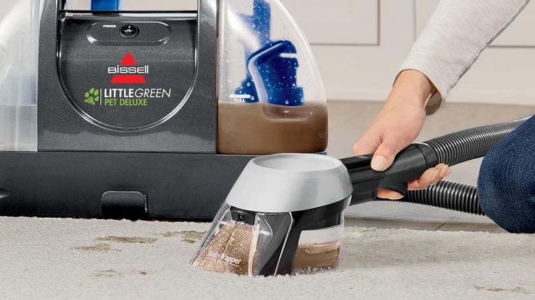 A person cleans a carpet with the Bissell Little Green Pet Deluxe