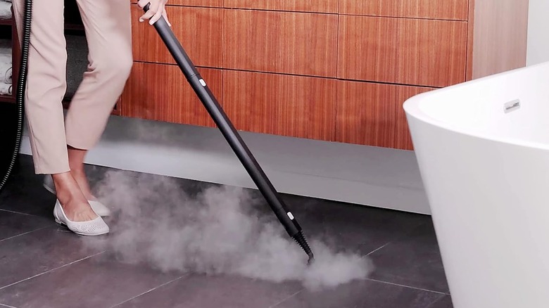 Person steam cleaning tiles