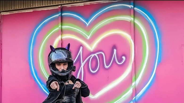 Girl pointing with a motorcycle helmet and heart light behind her