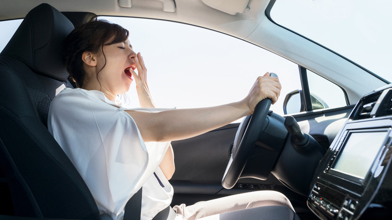 Woman yawning at car wheel